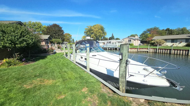 Yacht Photos Pics 2003 Sea Ray 340 Sundancer docked by a grassy waterfront, under a clear blue sky.
