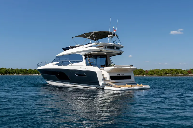 The Sun Yacht Photos Pics Luxury 2020 Prestige 590 yacht on serene blue water, clear sky backdrop.