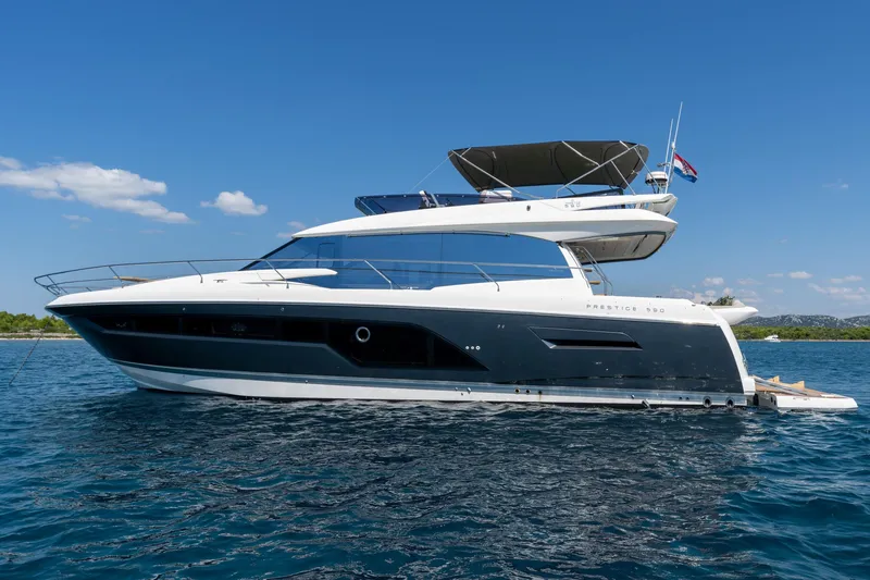 The Sun Yacht Photos Pics Luxury 2020 Prestige 590 yacht cruising on clear blue waters under a sunny sky.