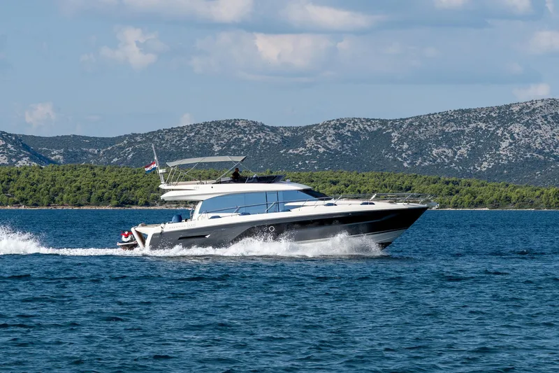 The Sun Yacht Photos Pics Luxury 2020 Prestige 590 yacht cruising on scenic blue waters with mountainous backdrop.
