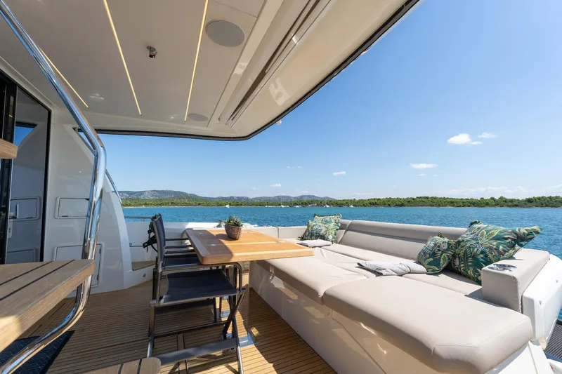 The Sun Yacht Photos Pics Luxurious 2020 Prestige 590 yacht deck with seating, table, and ocean view.