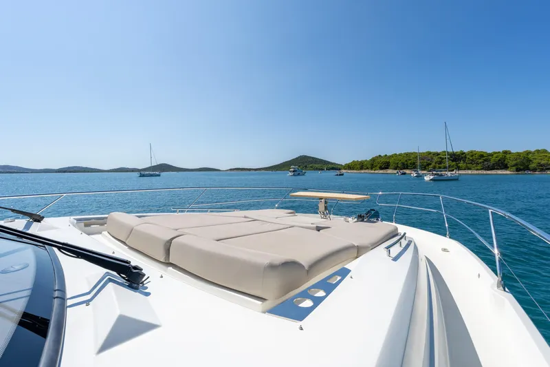 The Sun Yacht Photos Pics Prestige 590 yacht deck with sunbeds, 2020 model, overlooking serene blue waters and distant boats.