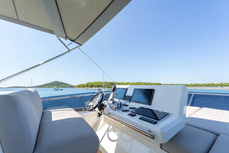 The Sun Yacht Photos Pics Flybridge of 2020 Prestige 590 yacht with modern controls, overlooking serene blue waters.