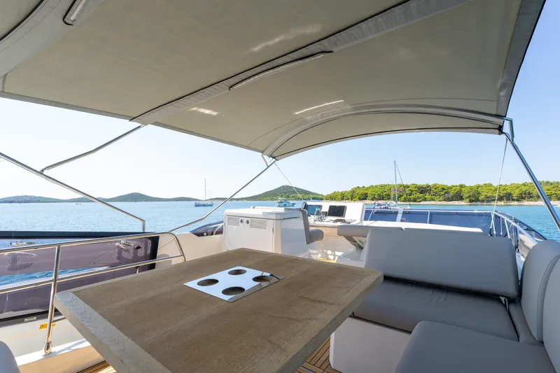 The Sun Yacht Photos Pics Luxurious 2020 Prestige 590 yacht deck with seating, table, and scenic ocean view.