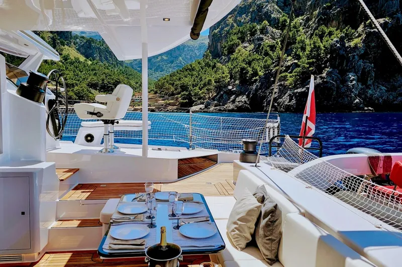 Yacht Photos Pics Luxurious 2016 HH66 catamaran with elegant deck dining, scenic ocean view, and lush green mountains.