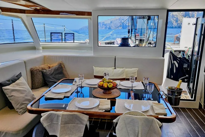  Yacht Photos Pics Luxurious interior of 2016 HH Catamarans HH66 with elegant dining setup and ocean view.