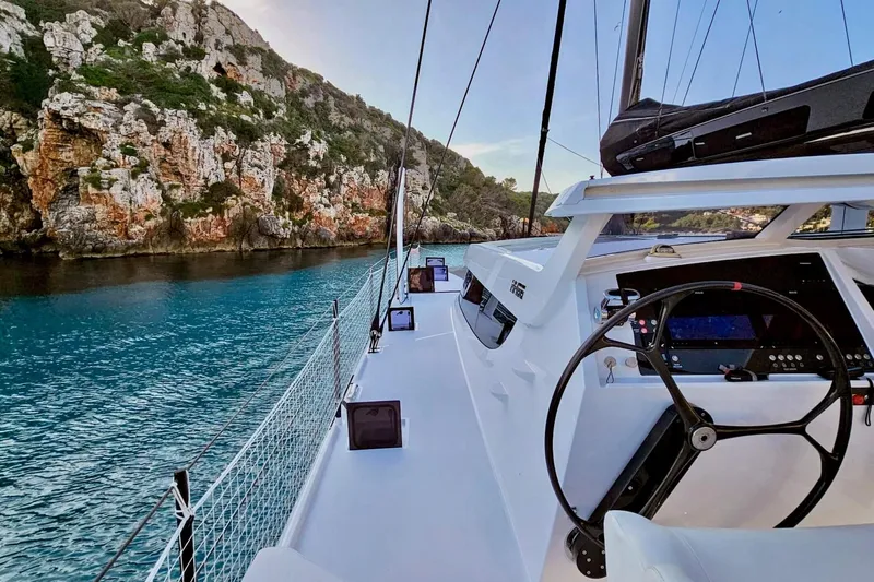  Yacht Photos Pics 2016 HH Catamarans HH66 sailing near rocky coastline with clear blue water.