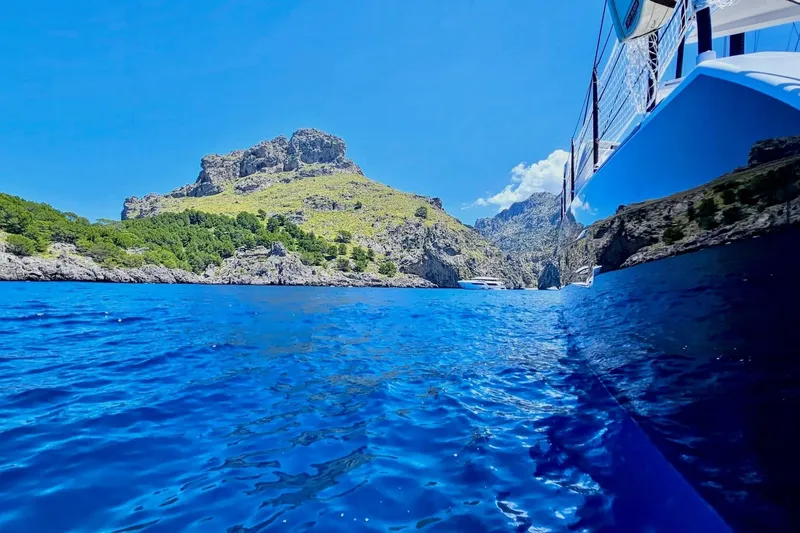  Yacht Photos Pics 2016 HH Catamarans HH66 sailing near rocky coastline with clear blue water.