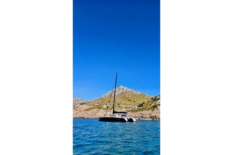  Yacht Photos Pics 2016 HH Catamarans HH66 sailing near rocky coastline under clear blue sky.