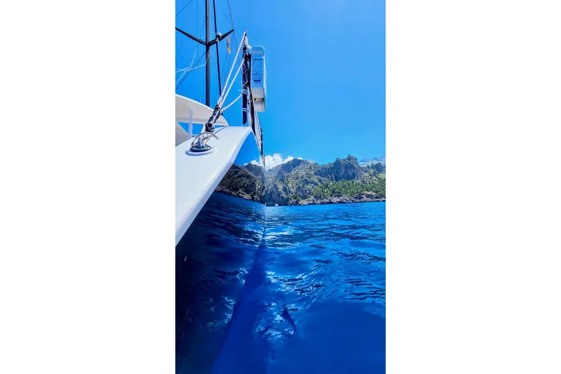  Yacht Photos Pics 2016 HH Catamarans HH66 sailing near rocky coastline under clear blue sky.
