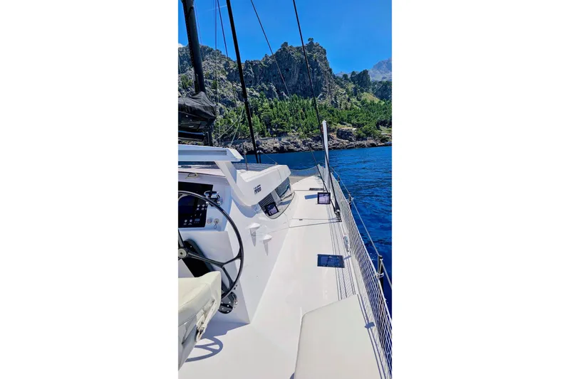  Yacht Photos Pics 2016 HH Catamarans HH66 sailing near rocky coastline under clear blue sky.