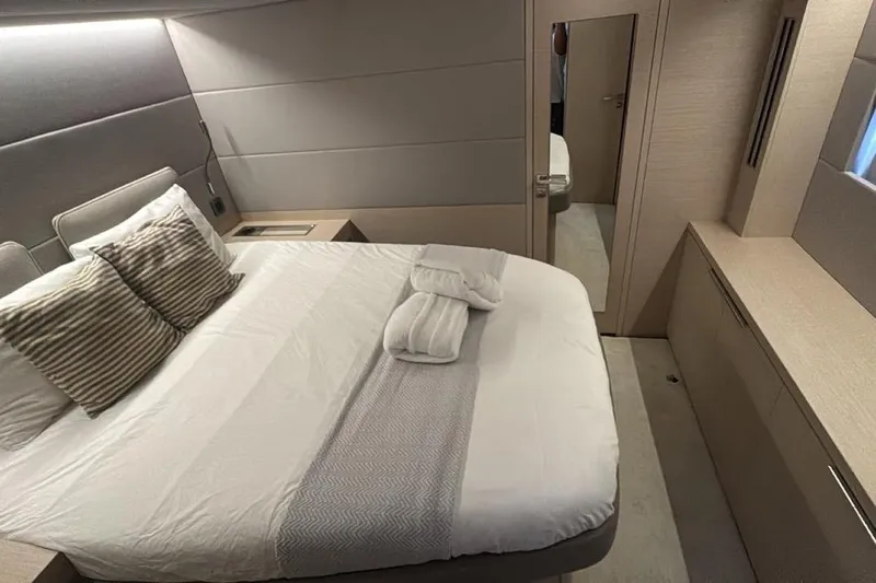 Va Bene Yacht Photos Pics Luxurious bedroom interior of 2022 Lagoon 55 yacht with modern design and cozy bedding.