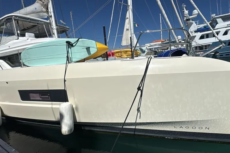 Va Bene Yacht Photos Pics 2022 Lagoon 55 yacht docked with surfboard and equipment on deck.