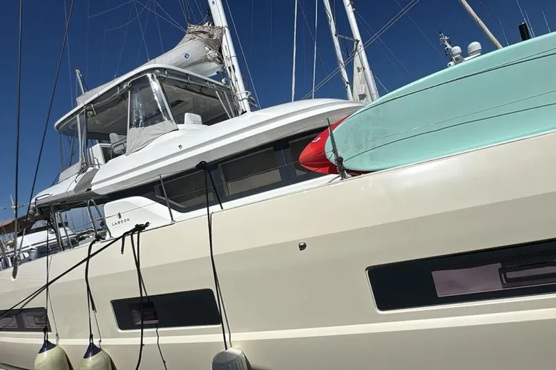Va Bene Yacht Photos Pics Lagoon 55 catamaran, 2022 model, docked with paddleboards on deck under clear blue sky.