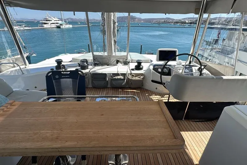 Va Bene Yacht Photos Pics Luxurious Lagoon 55 yacht cockpit with wooden table, helm, and ocean view, 2022 model.