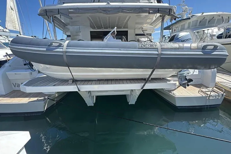 Va Bene Yacht Photos Pics 2022 Lagoon 55 yacht with inflatable dinghy on stern platform, docked in marina.