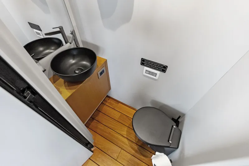 Matzu II Yacht Photos Pics Modern yacht bathroom with black sink, wooden flooring, and compact toilet in Wally WHY 150, 2023.