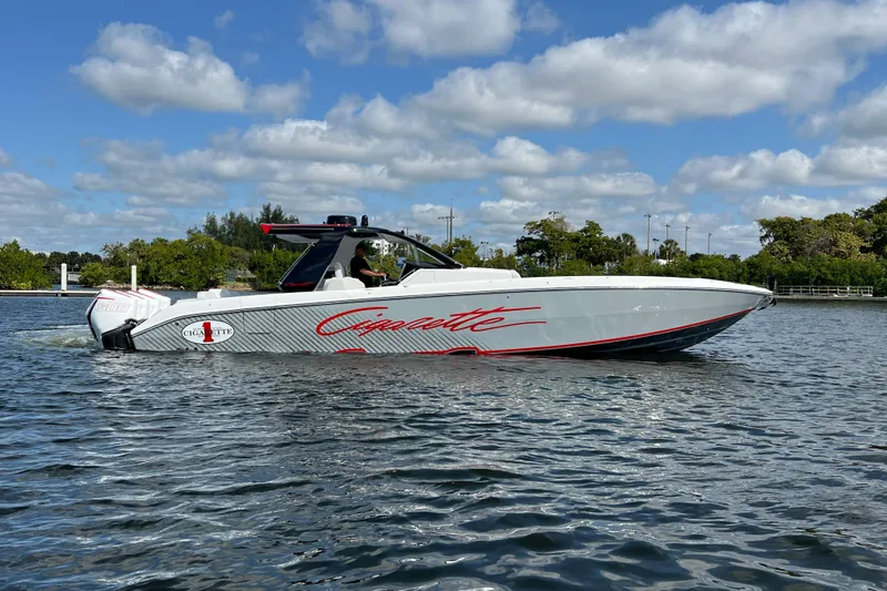  Yacht Photos Pics 2025 Cigarette 41 Nighthawk boat cruising on a sunny day, surrounded by lush greenery.