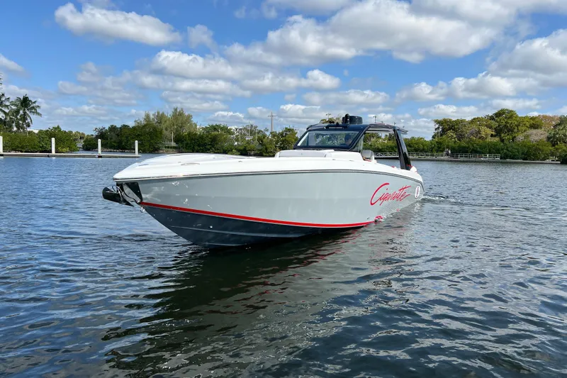  Yacht Photos Pics 2025 Cigarette 41 Nighthawk boat on calm water under a partly cloudy sky.