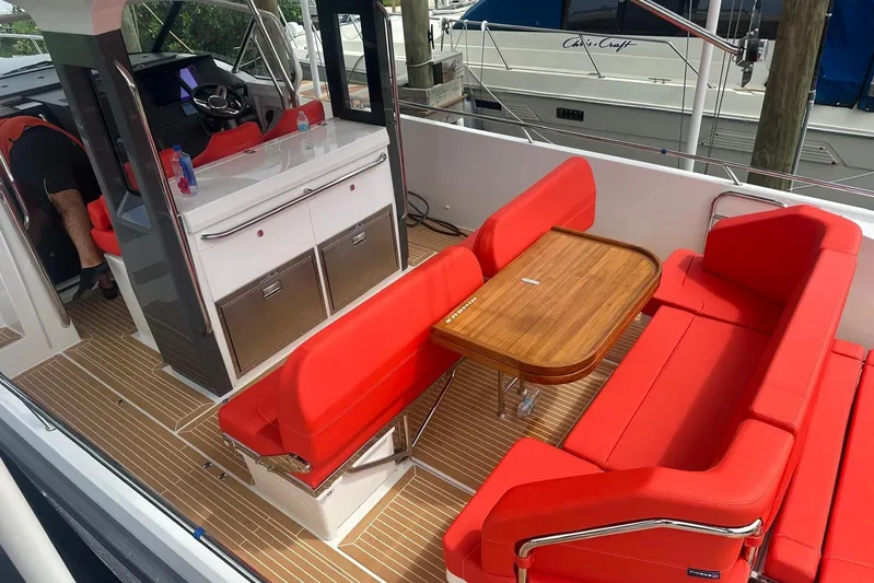  Yacht Photos Pics Luxurious 2025 Nimbus Tender 11 boat interior with red seating and wooden table.