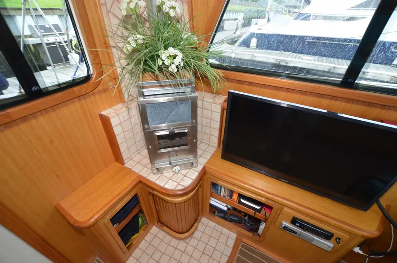 O Henry Yacht Photos Pics Interior of 2006 Legacy Yachts Sedan with TV, fireplace, and floral arrangement.