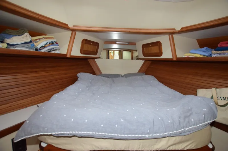 O Henry Yacht Photos Pics Cozy cabin interior of 2006 Legacy Yachts Sedan with neatly arranged bedding and wooden shelves.