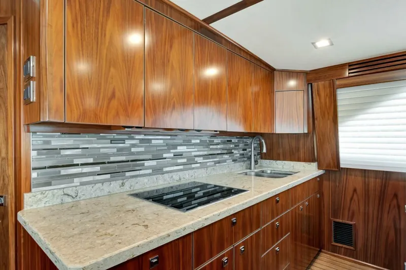 Desparado Yacht Photos Pics Luxurious kitchen interior of 2019 Viking 68 Convertible yacht with wood cabinetry and modern backsplash.