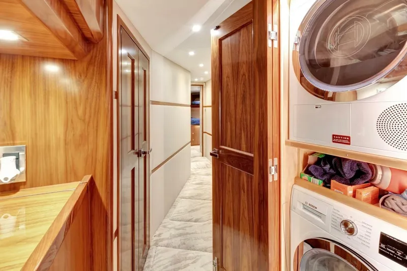Desparado Yacht Photos Pics Laundry area inside 2019 Viking 68 Convertible yacht, featuring wood paneling and modern appliances.