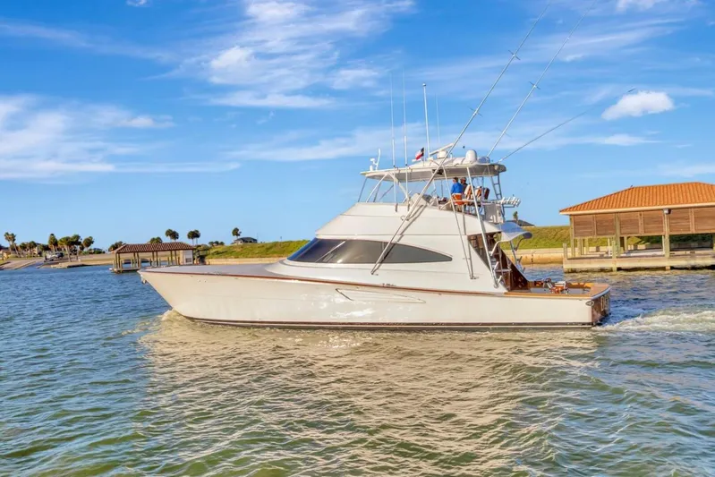 Desparado Yacht Photos Pics 2019 Viking 68 Convertible yacht cruising near a dock under a clear blue sky.