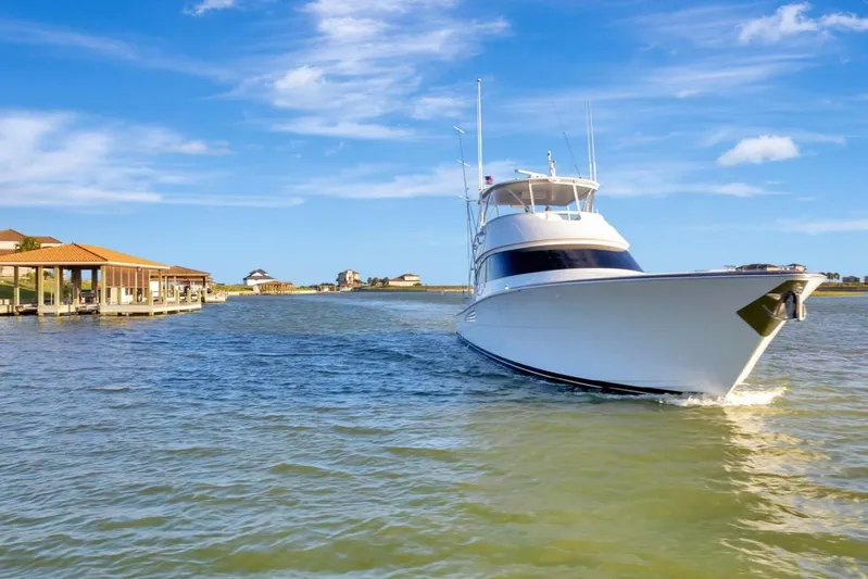 Desparado Yacht Photos Pics 2019 Viking 68 Convertible yacht cruising near waterfront homes under a clear blue sky.