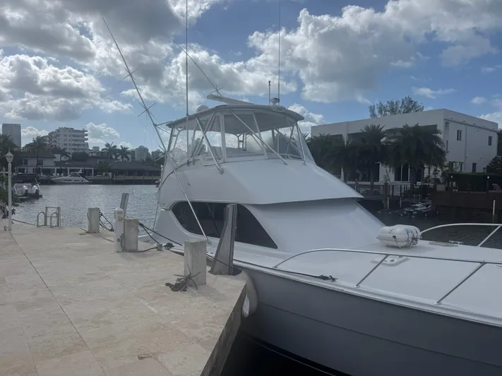 Audrey IV Yacht Photos Pics 2002 Hatteras 50 Convertible yacht docked by waterfront under cloudy sky.