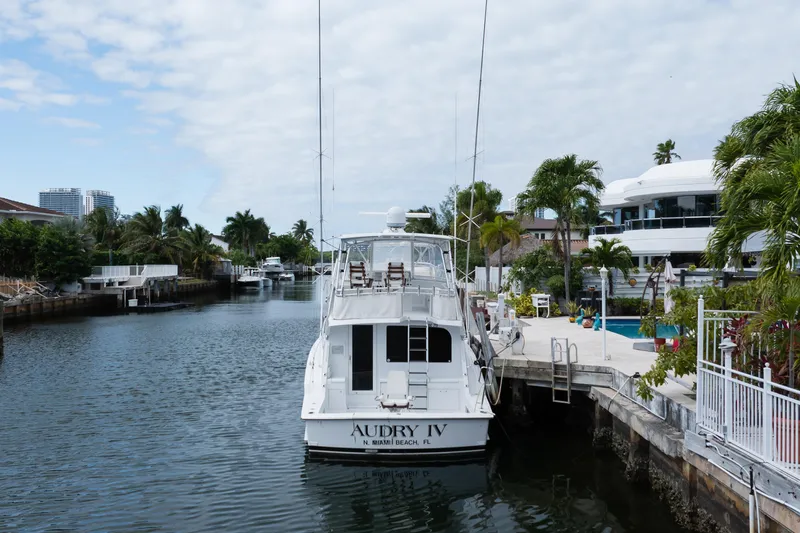 Audrey IV Yacht Photos Pics 2002 Hatteras 50 Convertible yacht docked in a scenic canal with palm trees.