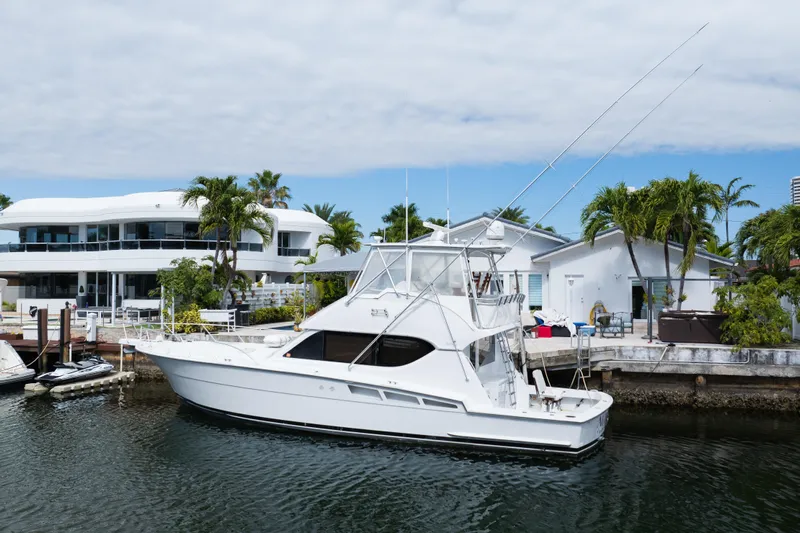 Audrey IV Yacht Photos Pics 2002 Hatteras 50 Convertible yacht docked near waterfront homes with palm trees.