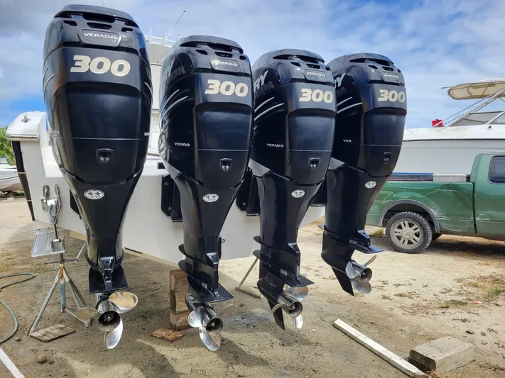  Yacht Photos Pics Four powerful outboard motors on a 2011 Motion Marine 42 boat, parked on a sandy surface.