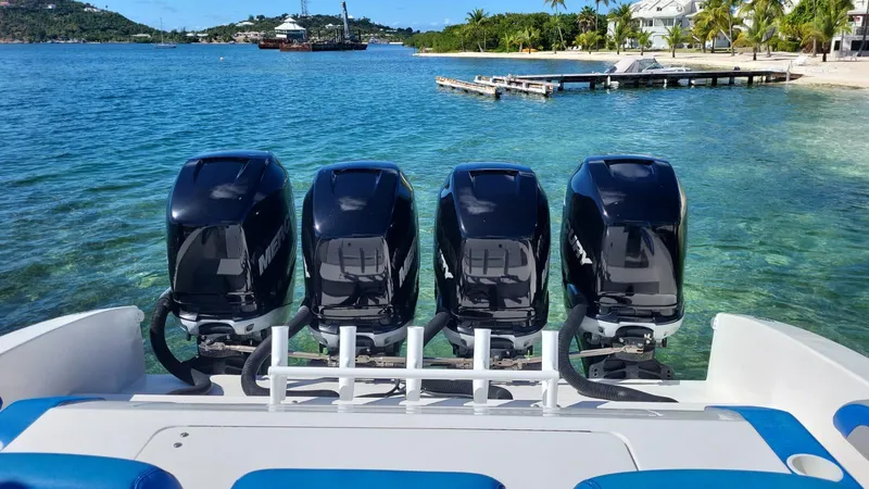  Yacht Photos Pics Four powerful outboard motors on a 2011 Motion Marine 42 boat, docked by a tropical shoreline.