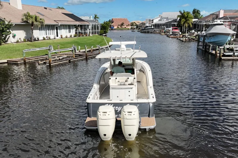  Yacht Photos Pics 2019 Scout 320 LXF boat navigating a residential canal with waterfront homes.