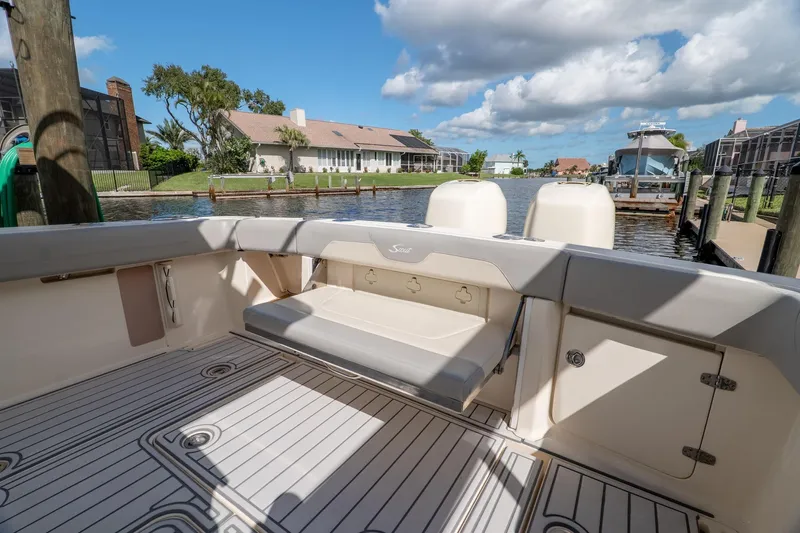 Yacht Photos Pics 2019 Scout 320 LXF boat interior with seating, docked by waterfront homes under blue sky.