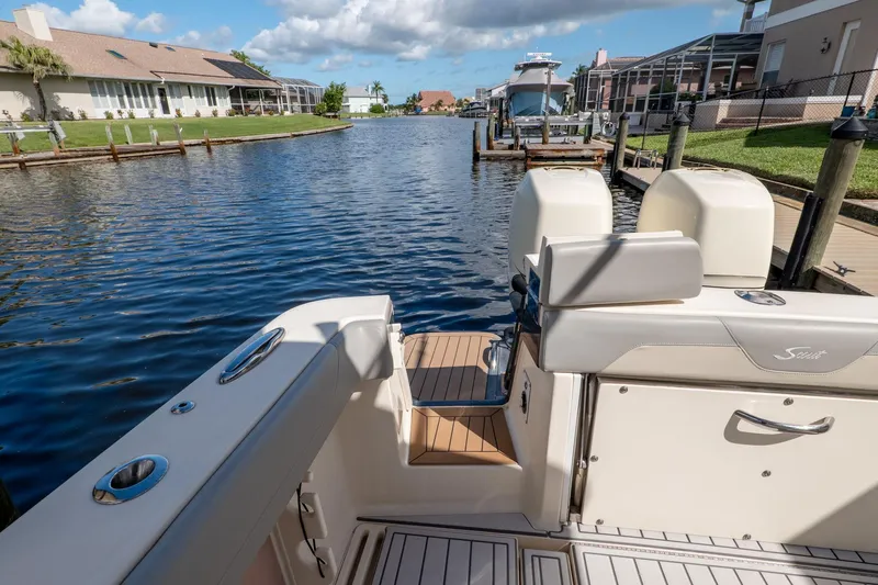 Yacht Photos Pics 2019 Scout 320 LXF boat docked in a scenic canal with clear blue water.