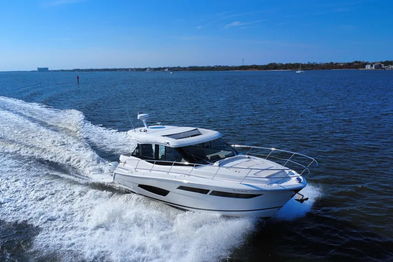 Irresistible Yacht Photos Pics 2021 Regal 38 XO yacht cruising on open water under clear blue skies.