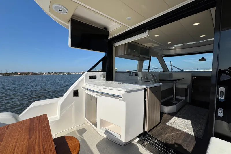 Irresistible Yacht Photos Pics Luxurious 2021 Regal 38 XO yacht interior with modern kitchen and seating area, overlooking serene waters.