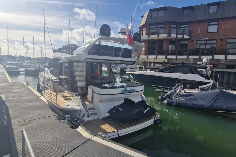 Alouise Yacht Photos Pics 2022 Galeon 460 Fly yacht docked at marina, surrounded by other boats and buildings.
