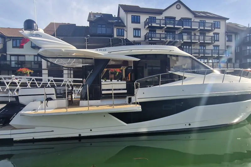 Alouise Yacht Photos Pics 2022 Galeon 460 Fly yacht docked near modern waterfront buildings.