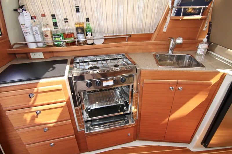  Yacht Photos Pics 2020 Ranger Tugs R-29 galley with stove, sink, and wooden cabinetry.