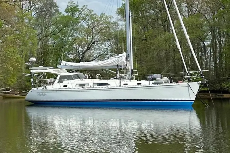 Starlight Yacht Photos Pics Sailboat Outbound 46, 2016 model, anchored on a calm river surrounded by trees.