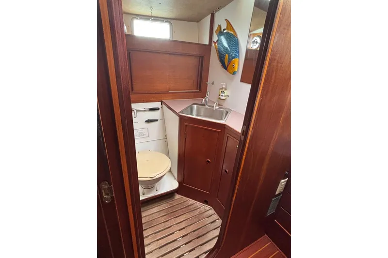 Prism Yacht Photos Pics 1984 Oyster 435 yacht bathroom with wooden interior and fish wall decor.