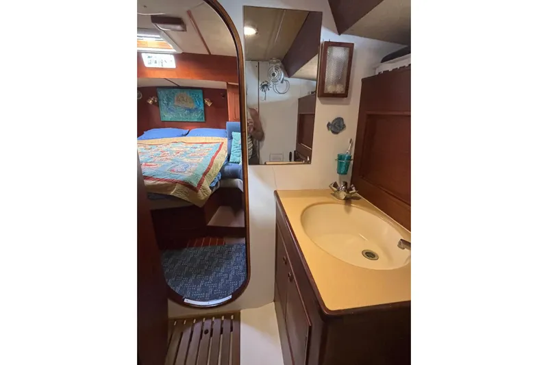 Prism Yacht Photos Pics 1984 Oyster 435 yacht interior with cozy bedroom and compact bathroom sink area.