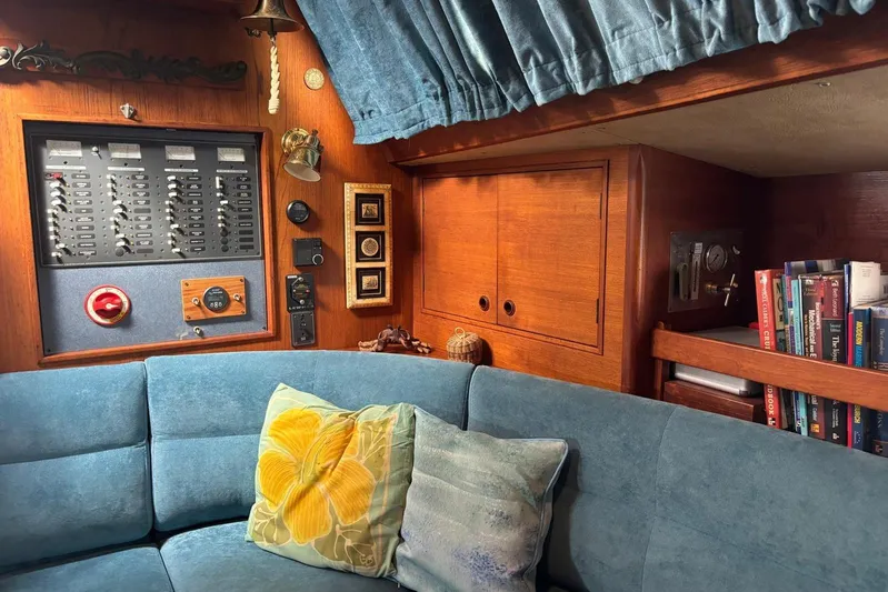 Prism Yacht Photos Pics Interior of 1984 Oyster 435 yacht with blue sofa, control panel, and bookshelf.