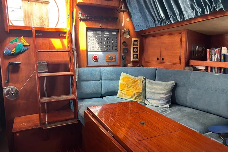 Prism Yacht Photos Pics Interior of a 1984 Oyster 435 yacht with blue seating and wooden accents.