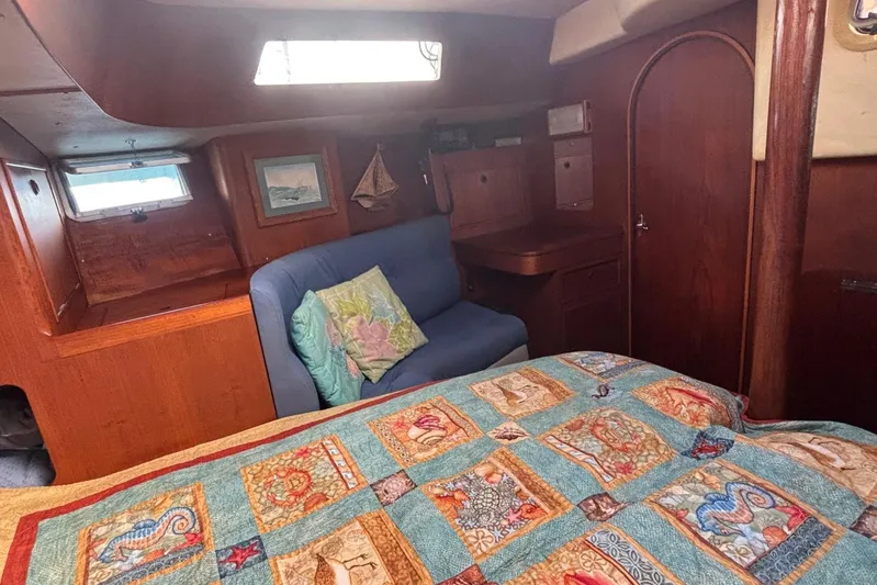 Prism Yacht Photos Pics Cozy cabin interior of 1984 Oyster 435 sailboat with colorful quilt and wooden furnishings.