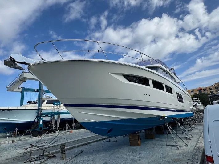 Ain't Settlin! Yacht Photos Pics 2013 Prestige 550 Flybridge yacht on dry dock under a partly cloudy sky.